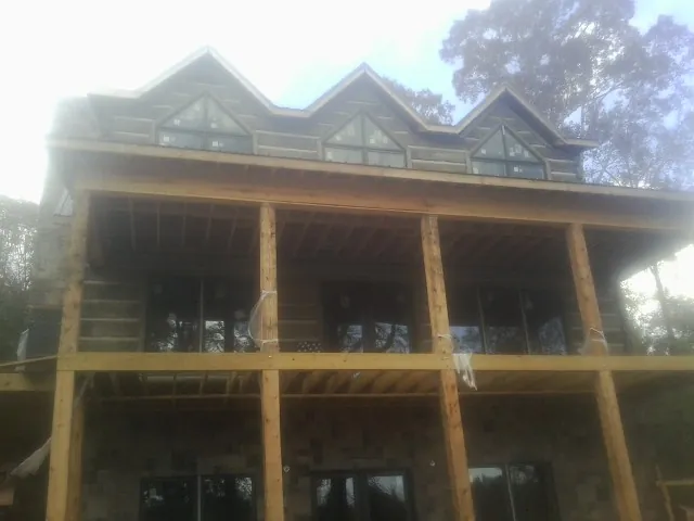 Dormers and porch framing on a large log home under construction — Roof Coating work by our crew in Dryden