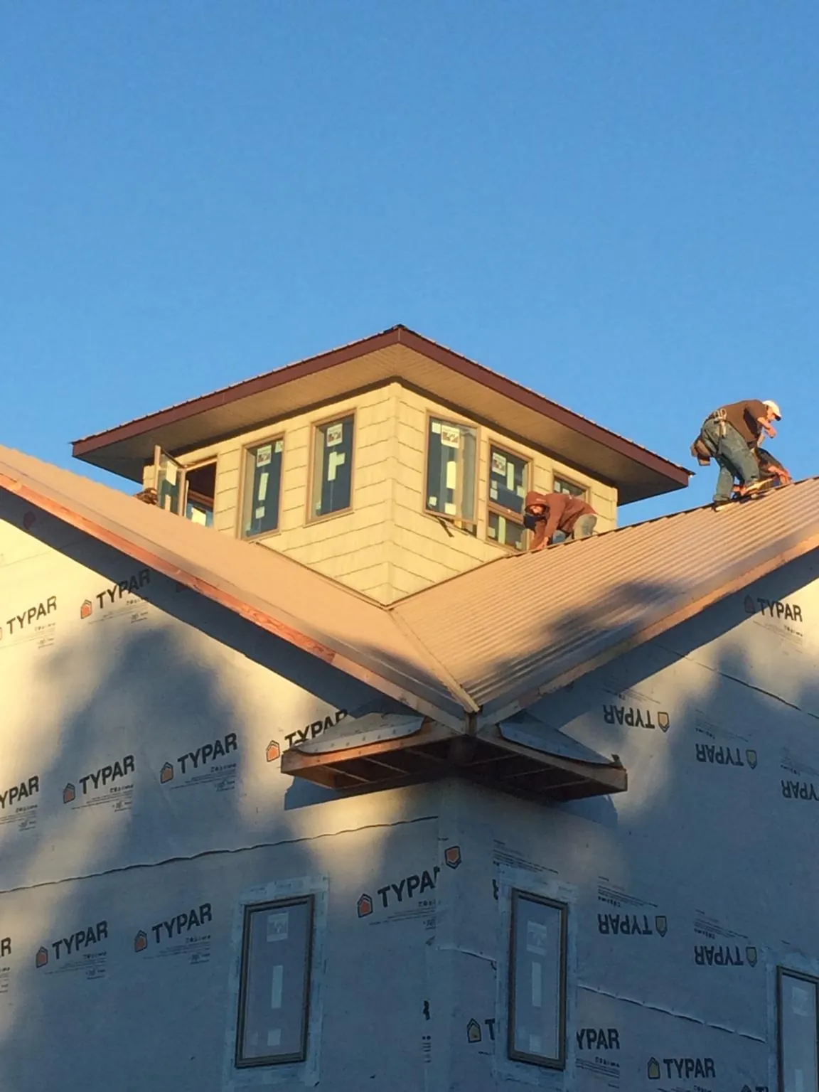 Roofers working around a rooftop cupola on a new metal roof at sunset — Roof Waterproofing in Dryden by Roofing Brothers